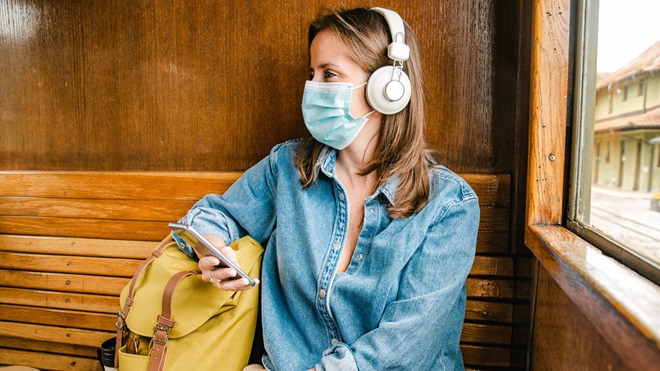 travel_insurance_pandemic_woman_on_train_wearing_mask